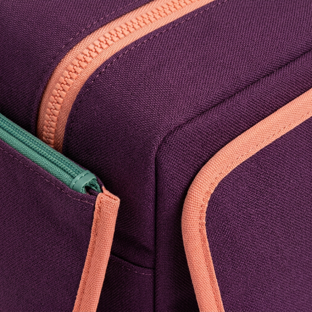 AI concept macro of aubergine textile, contrasting zippers and peach binding.