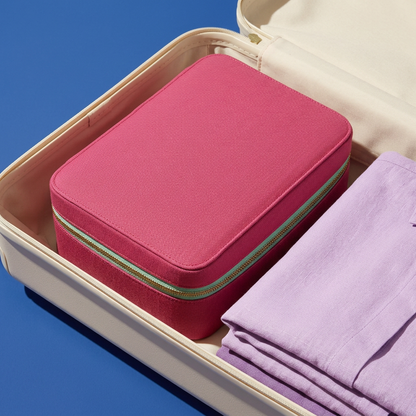 AI concept of the closed raspberry toiletry case packed beside lilac clothing in luggage.